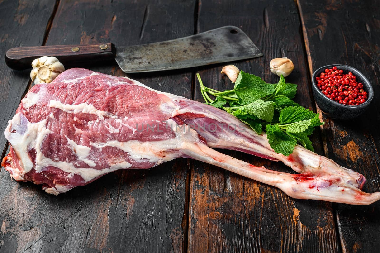 Whole raw leg of lamb. Fresh organic meat. Dark wooden background. Top view.