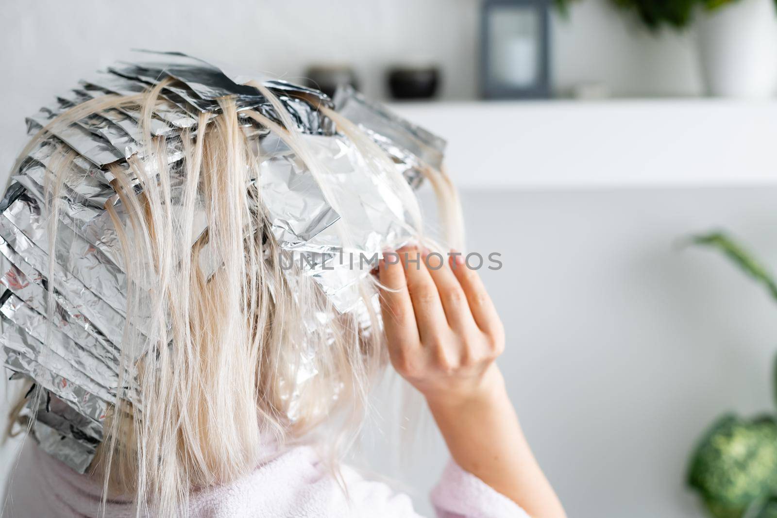 woman dyes her hair foil at home by Andelov13