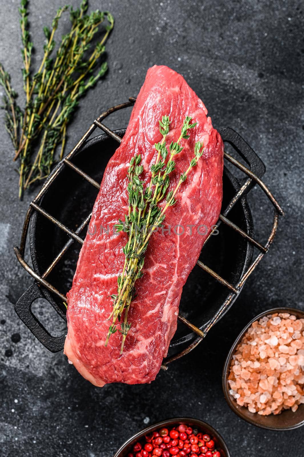 Raw Striploin steak on a grill, marbled beef. Black background. Top view.