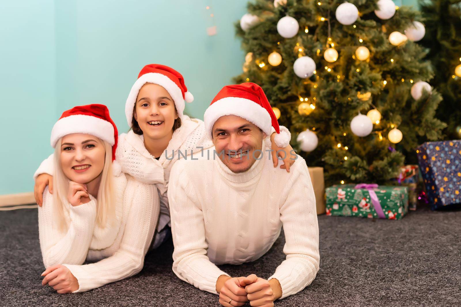 family, christmas, x-mas, winter, happiness and people concept - smiling family in santa helper hats with many gift boxes and bengal lights by Andelov13