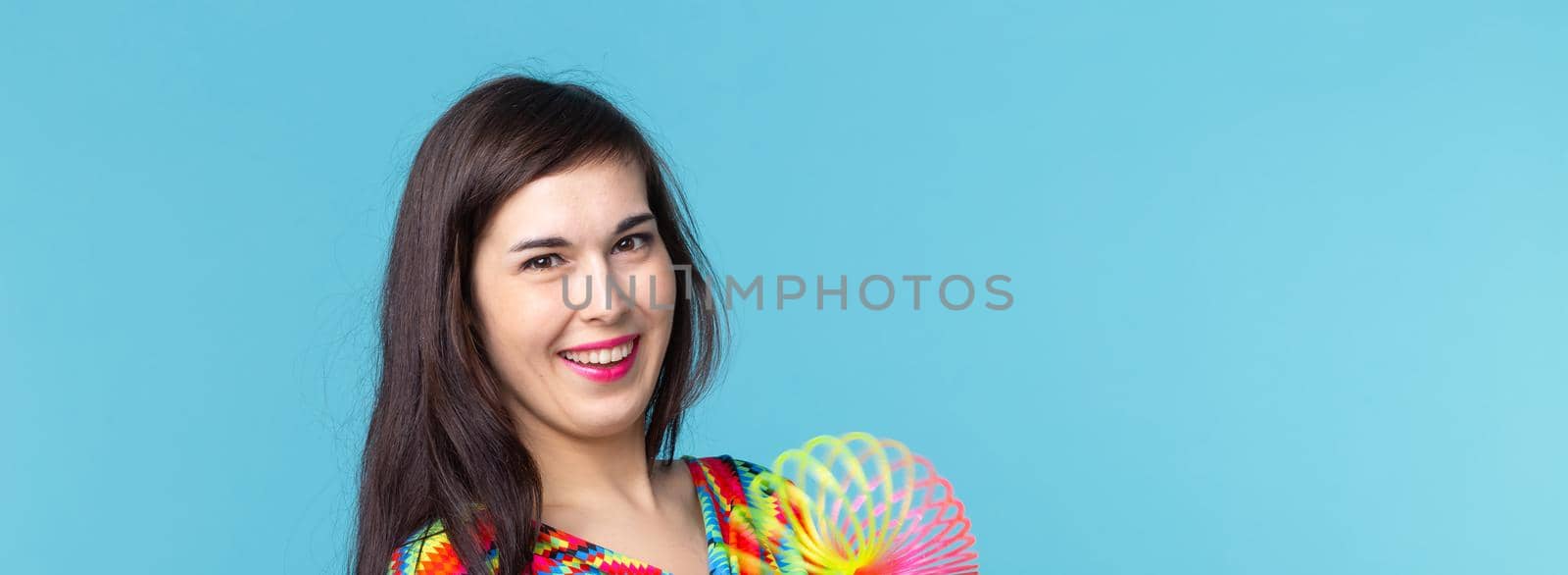 UFA, RUSSIA - MAY 26, 2017 : young woman playing with a slinky on blue background.
