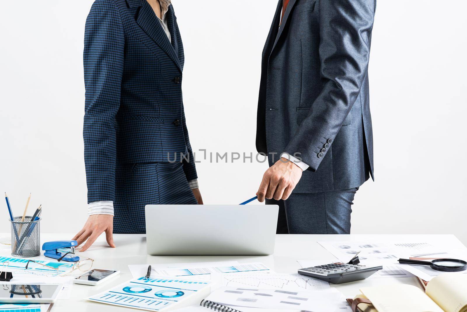 Business consultation and discussing with colleagues in office. Corporate teamwork and collaboration. Professional analysis of financial indexes. Businessman and businesswoman stand near desk