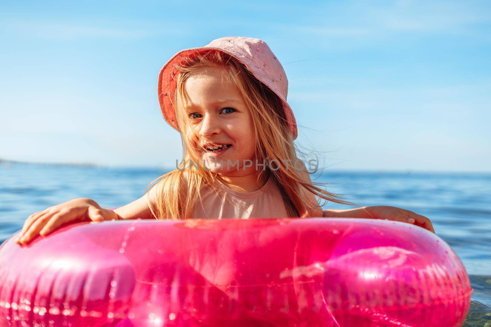 Girl kid in pink panama swimming in sea with pink circle