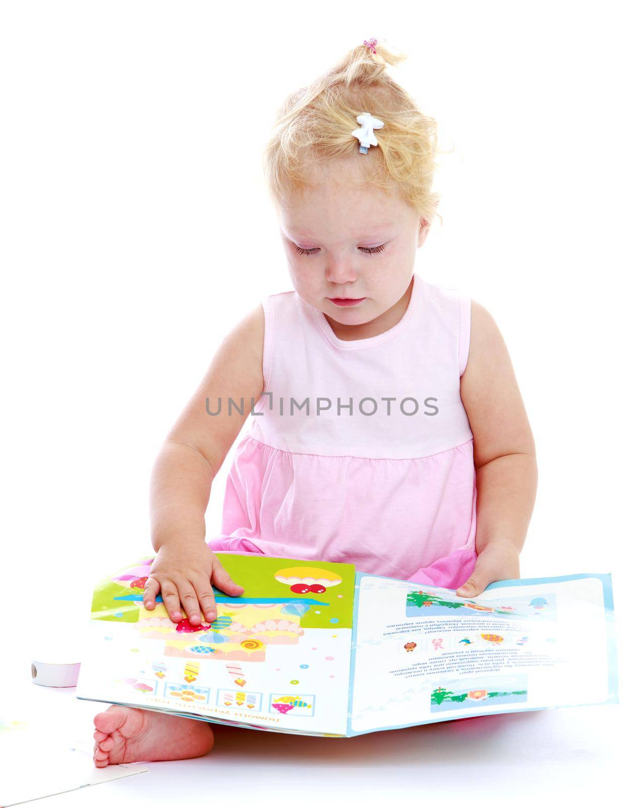 Adorable little girl reading a book sitting on the floor.Isolated on white background portrait.
