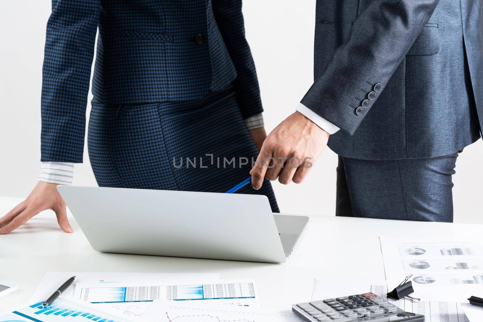 Businesspersons stand near desk with financial charts. Manager use laptop computer for presentation. Estimation and analyze of new startup project. Corporate teamwork concept with business people