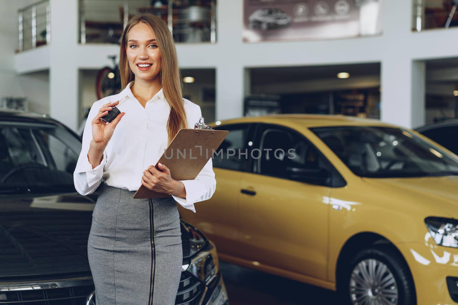 Young happy woman buyer/seller near the car with keys in hand close up