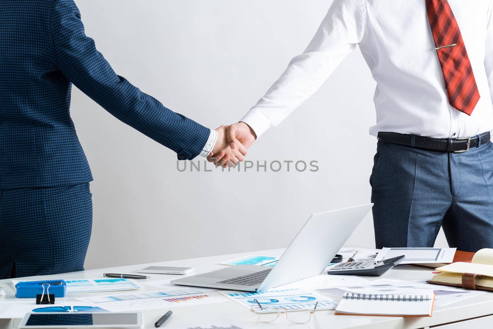 Businessman and businesswoman handshaking after good deal. Business consultation and cooperation in office. Corporate teamwork and partnership. Businesspersons greeting or finishing successful meeting