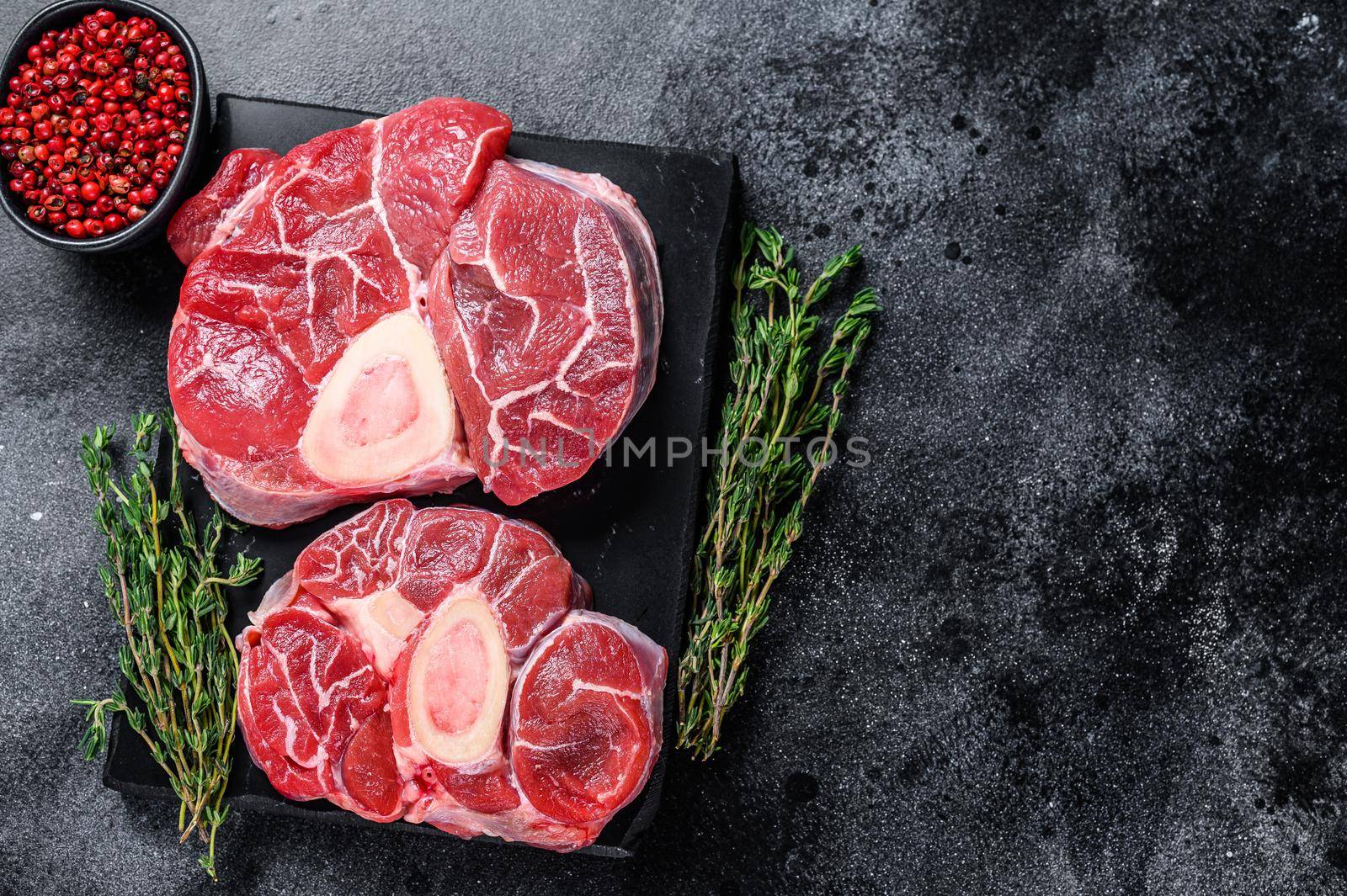 Raw beef meat osso buco shank steak, italian ossobuco. Black background. Top view. Copy space by Composter