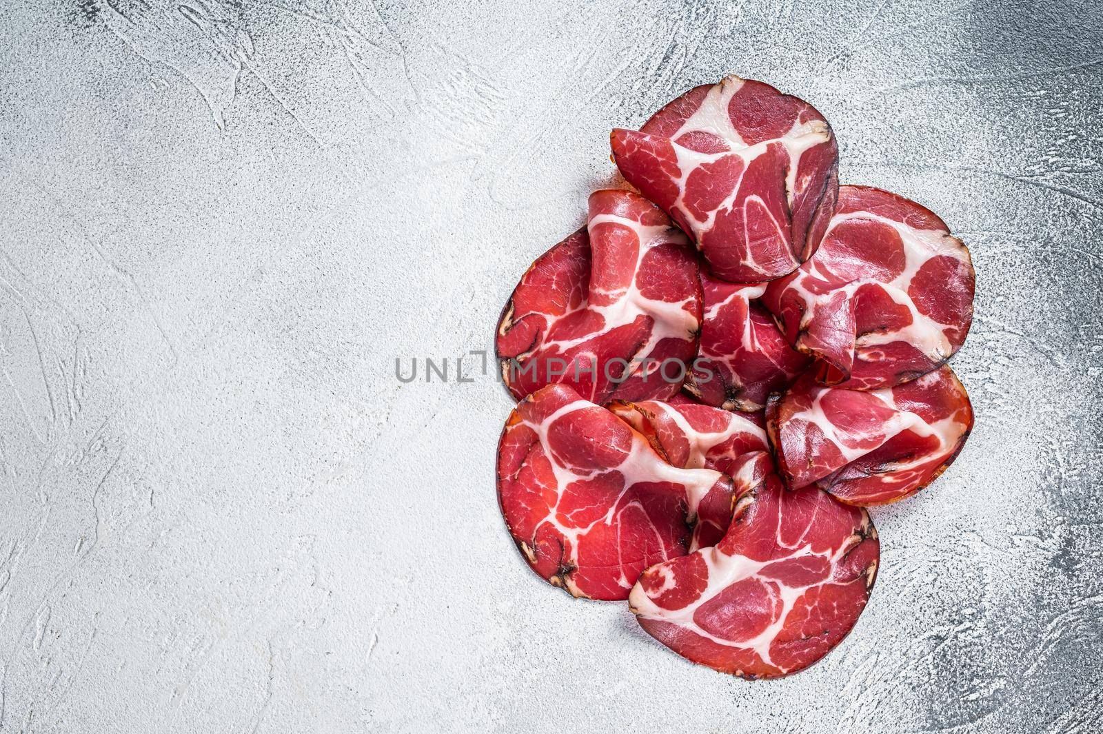 Coppa Cured ham on kitchen table. White background. Top view. Copy space by Composter