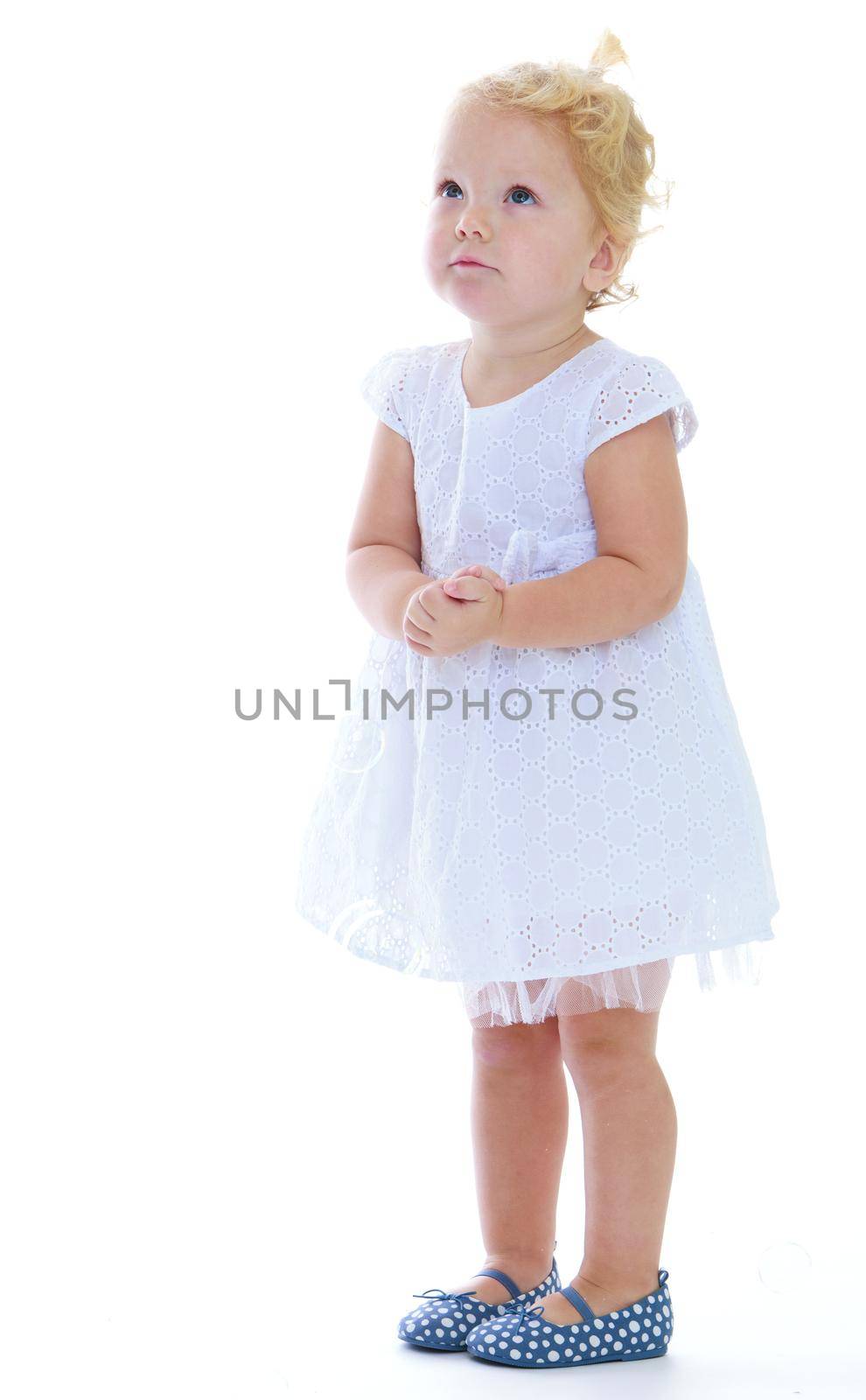 Very small charming little girl in a white dress. Isolated on white background .
