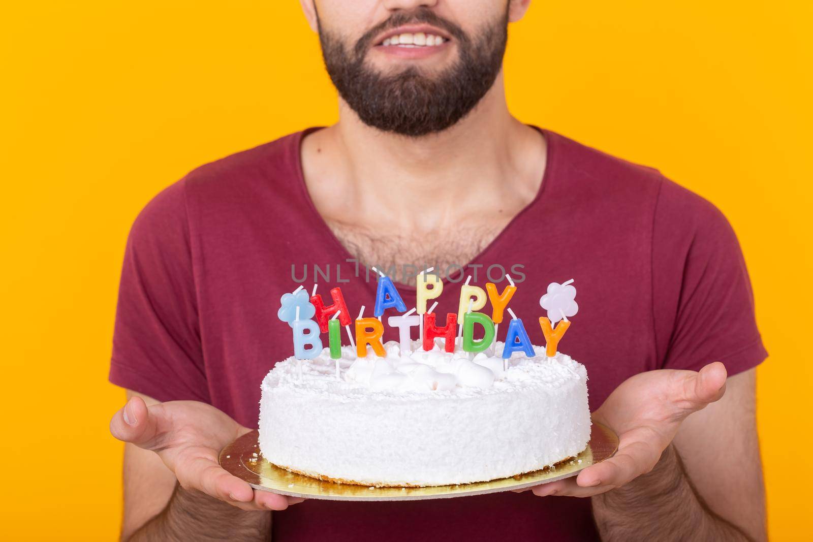 Unidentified young male hipster with a beard holding a cake with the inscription happy birthday congratulations on the anniversary and the holiday. Concept of promotions and discounts