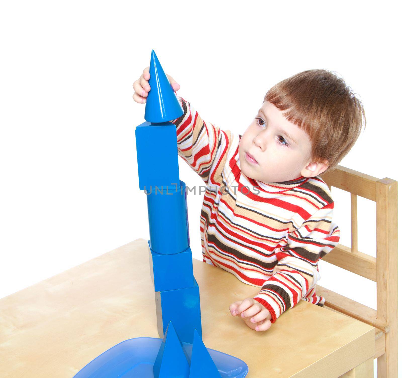 Little boy builds a blue pyramid.Isolated on white background portrait.