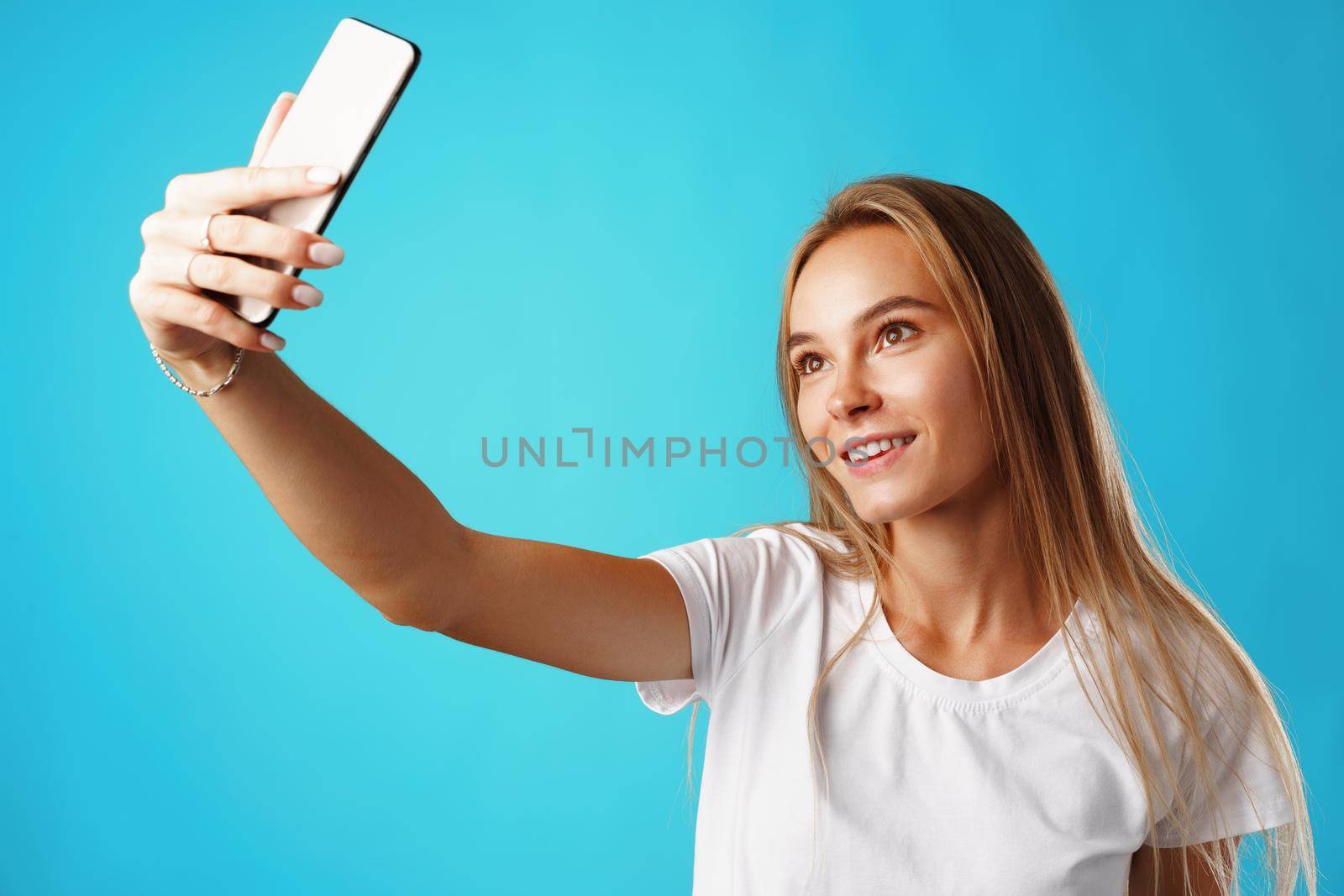 Happy casual young woman smiling and having a video call on smartphone