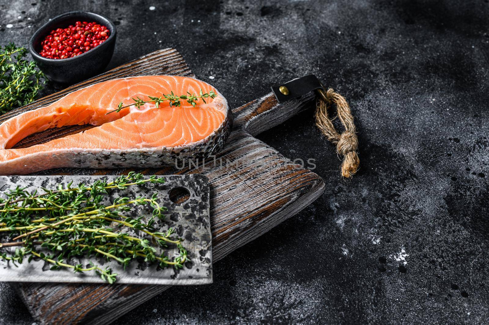 Uncooked salmon sliced in the form of a steak with pepper. Black background. Top view. Copy space.