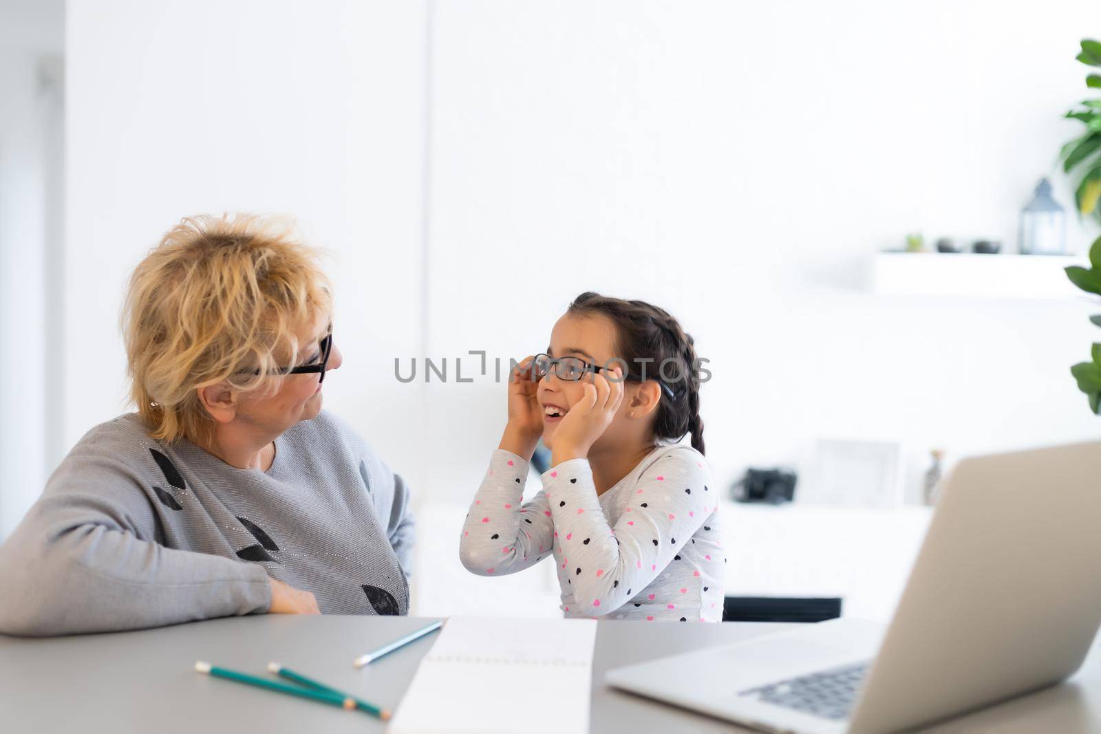 Helpful granny. Helpful loving granny assisting her cute granddaughter making homework