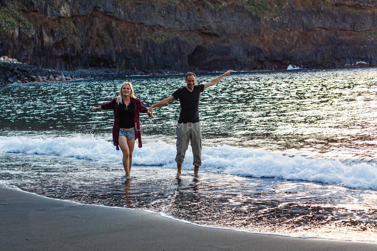 Vacation couple walking on beach together in love holding around each other. Happy interracial young couple, Asian woman and Caucasian man.