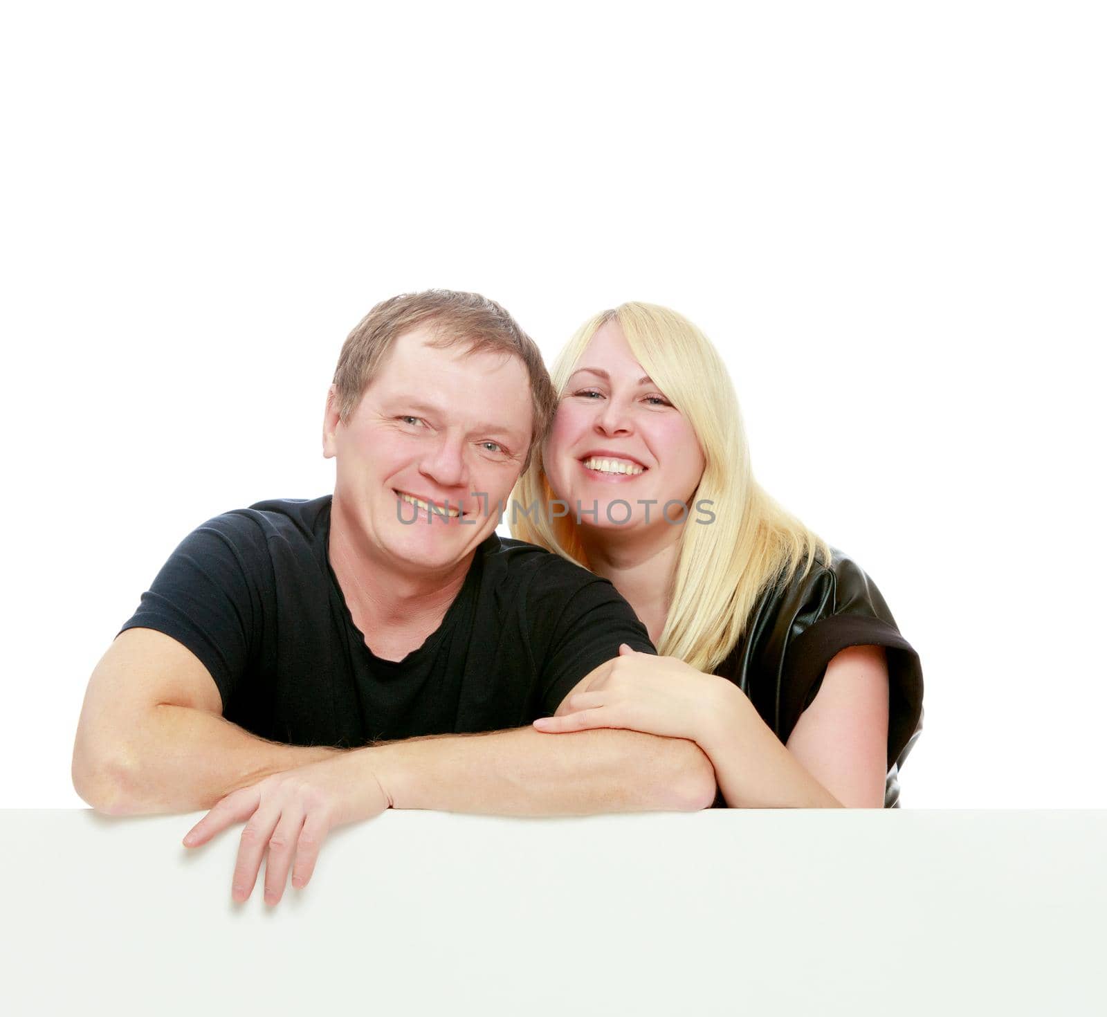 A man and a woman tenderly hugging each other. Peeping over white banner.Isolated on white background.