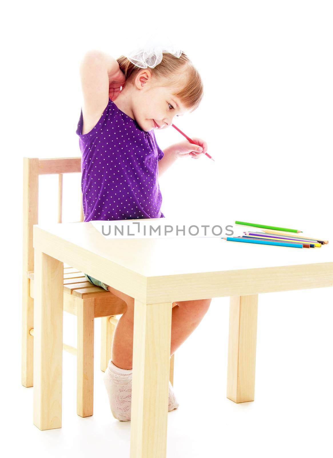 Happy childhood, adolescence, the development of the family concept.Little girl draws pencils sitting at the table. Isolated on white background.