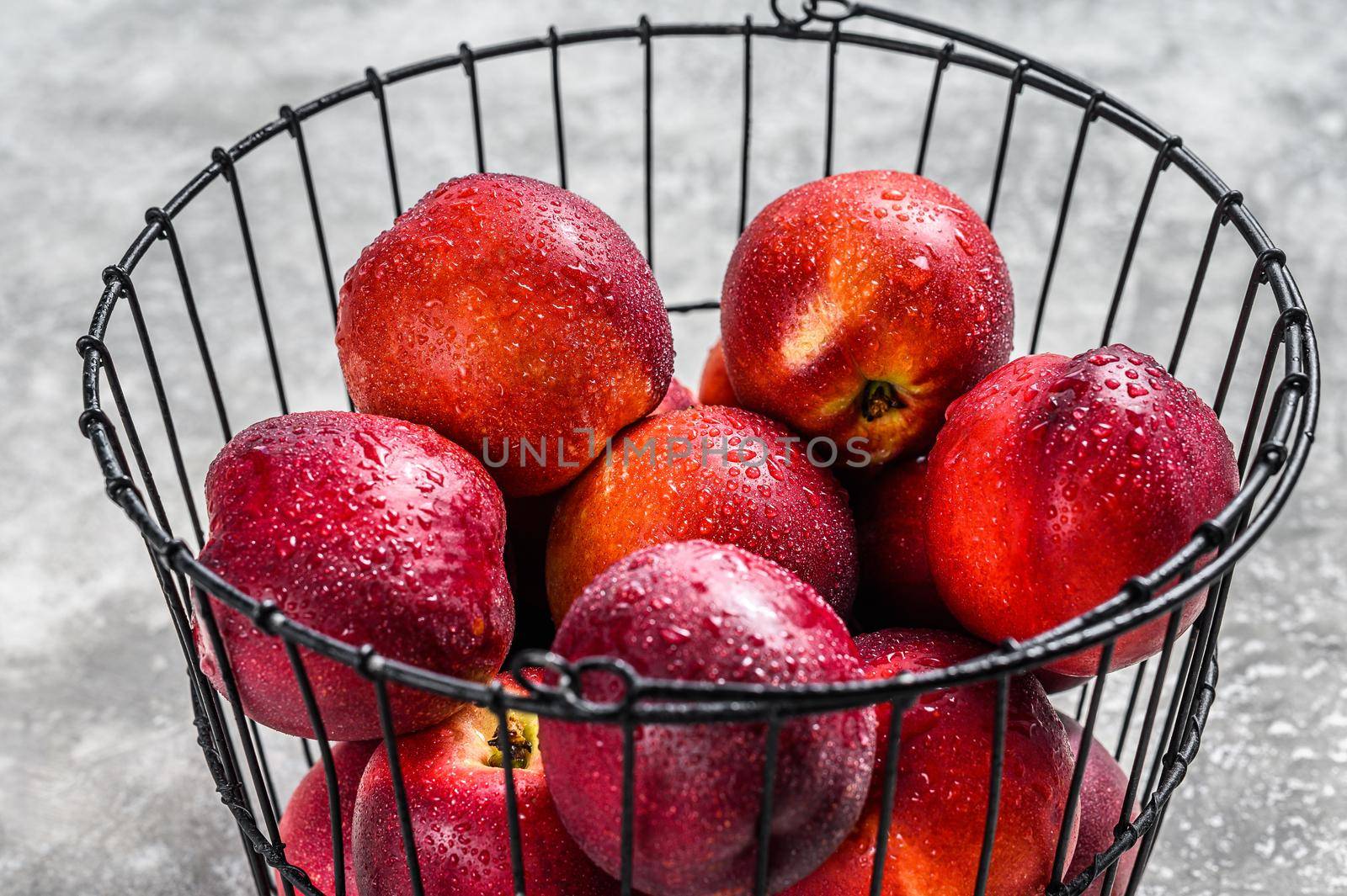 Ripe red nectarines in a basket. Gray background. Top view by Composter