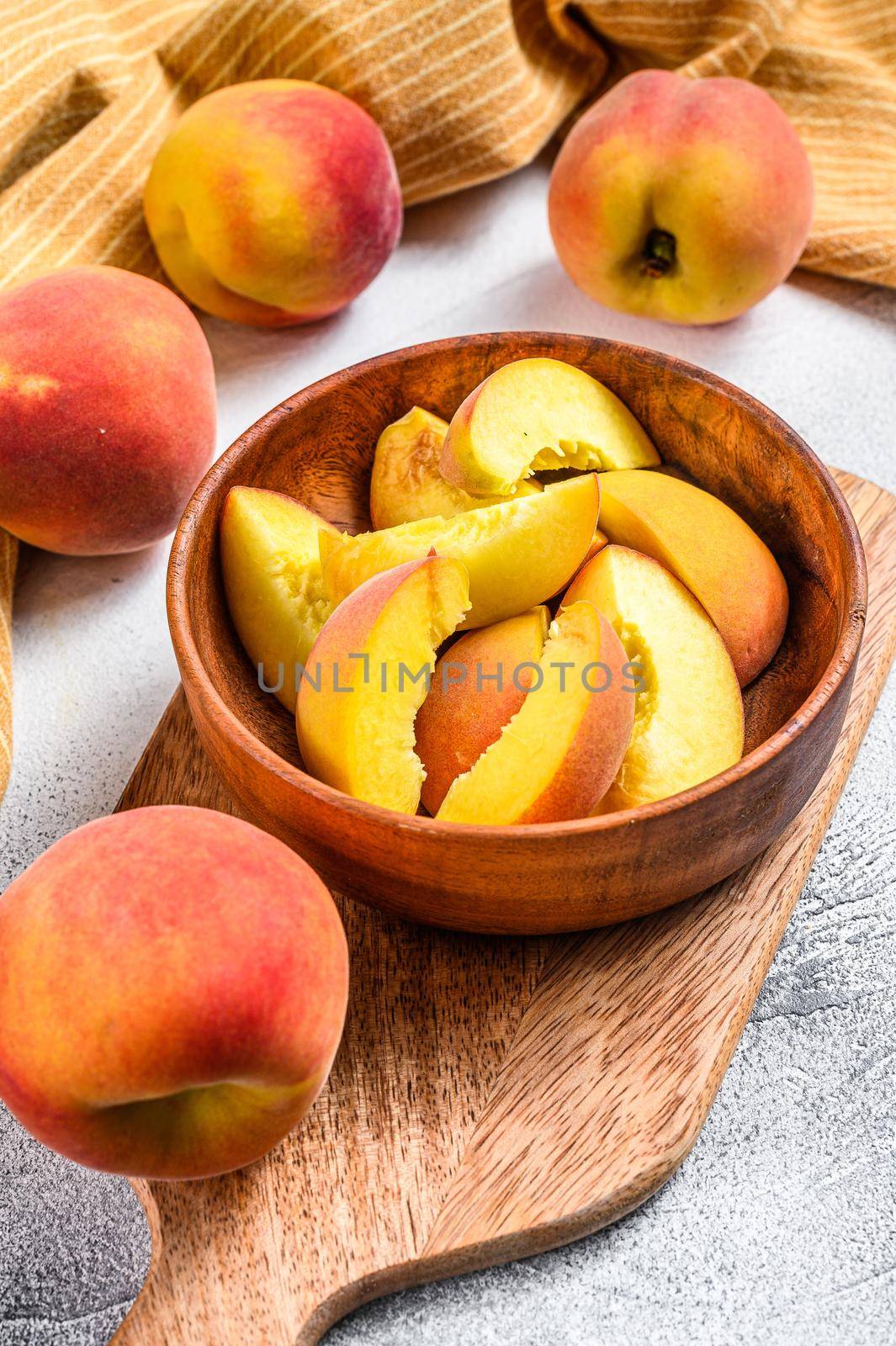 Sliced Peaches, organic fruit in a wooden bowl. Gray background. Top view.