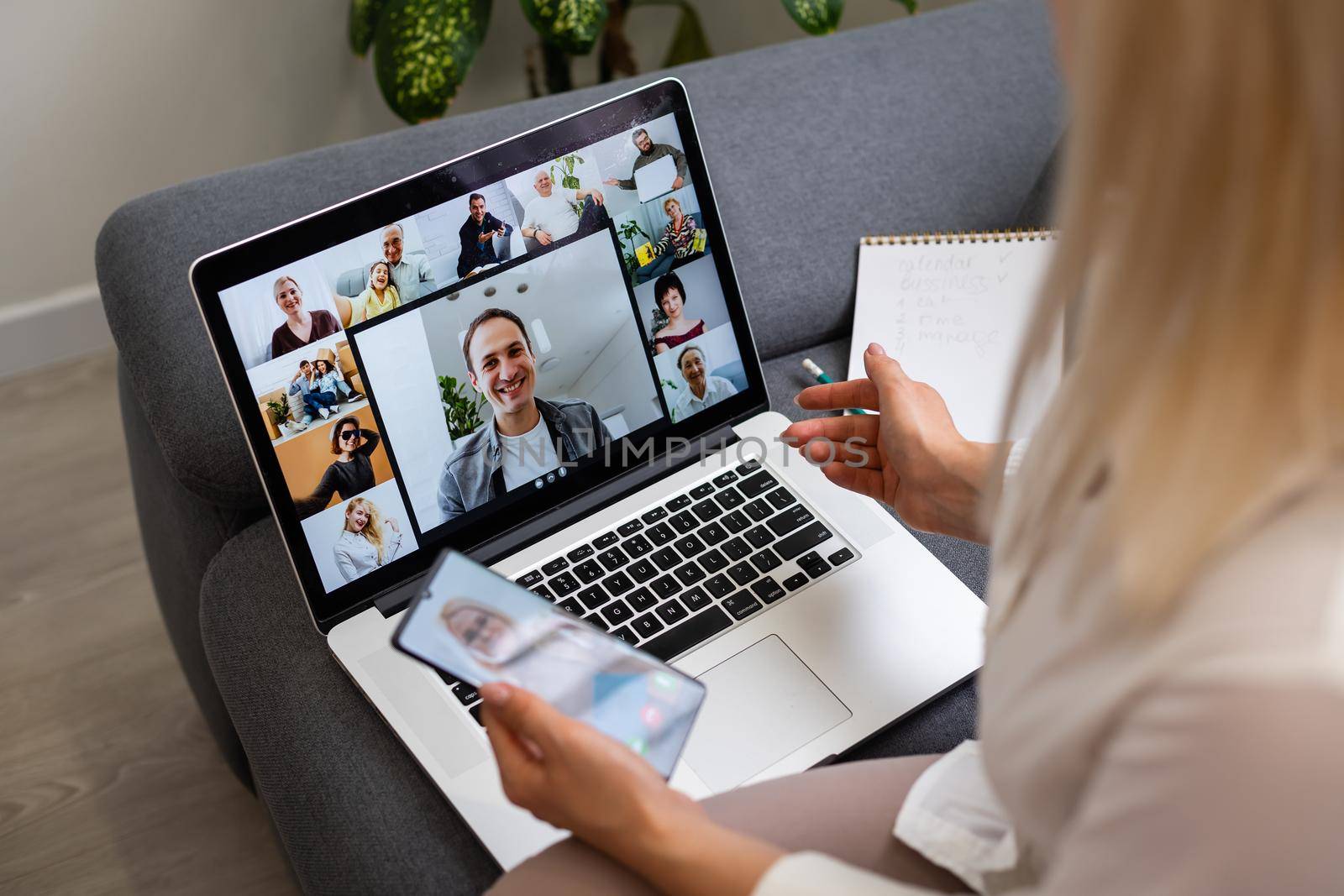 Back view of business woman talking to her colleagues about plan in video conference. Multiethnic business team using laptop for a online meeting in video call. Group of people smart working from home