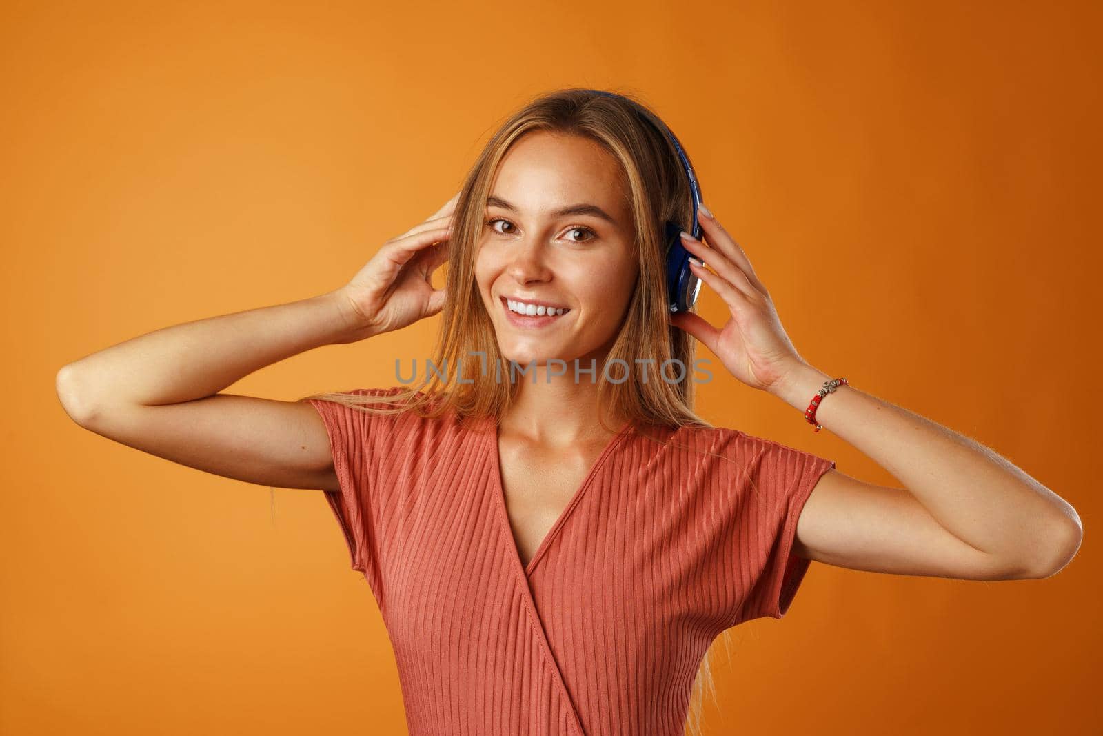 Positive young woman listening to music with blue headphones close up