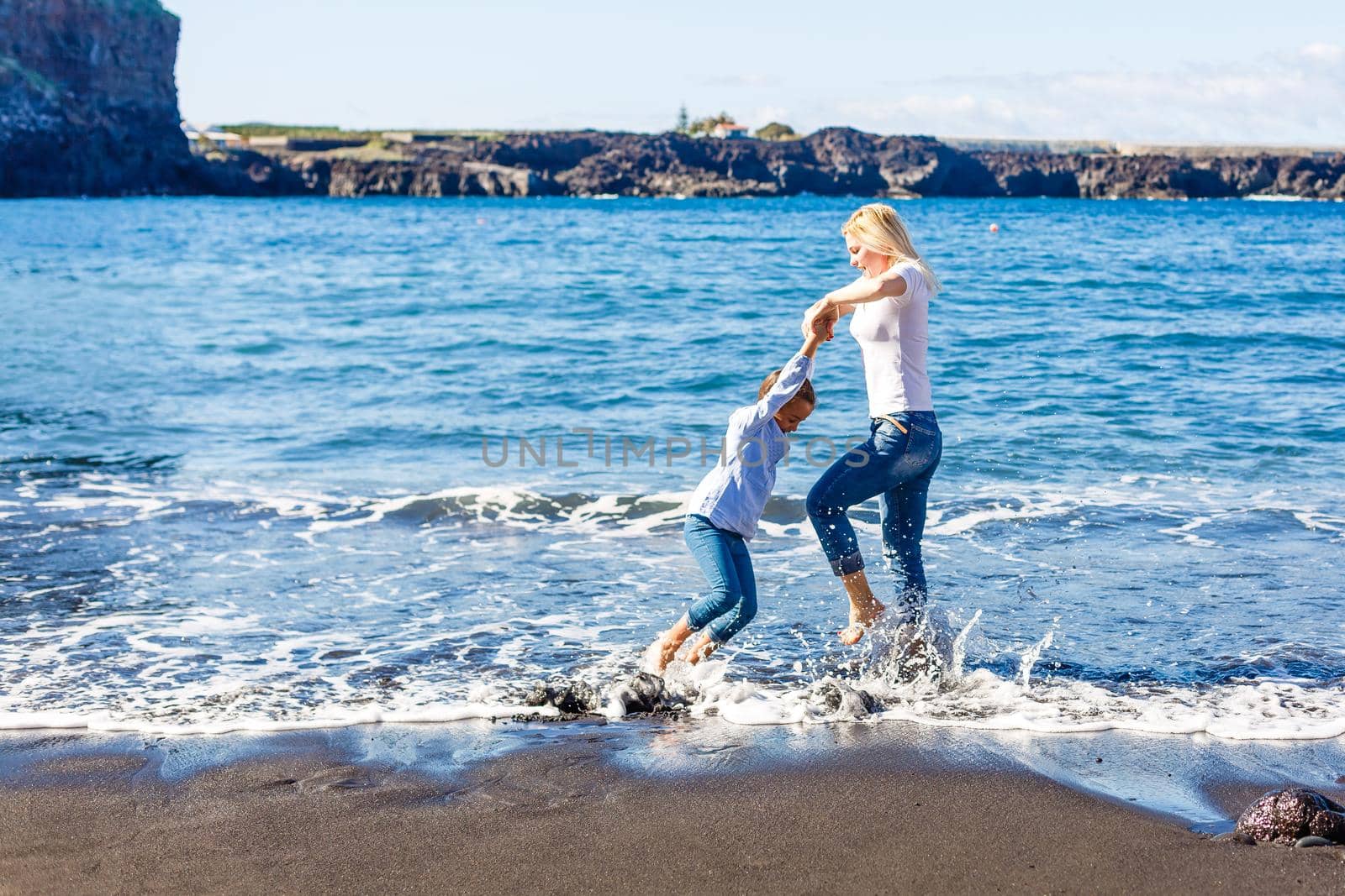 Family holiday on Tenerife, Spain. Mother with children outdoors on ocean. Portrait travel tourists - mom with kids. Positive human emotions, active lifestyles. Happy young family on sea beach by Andelov13