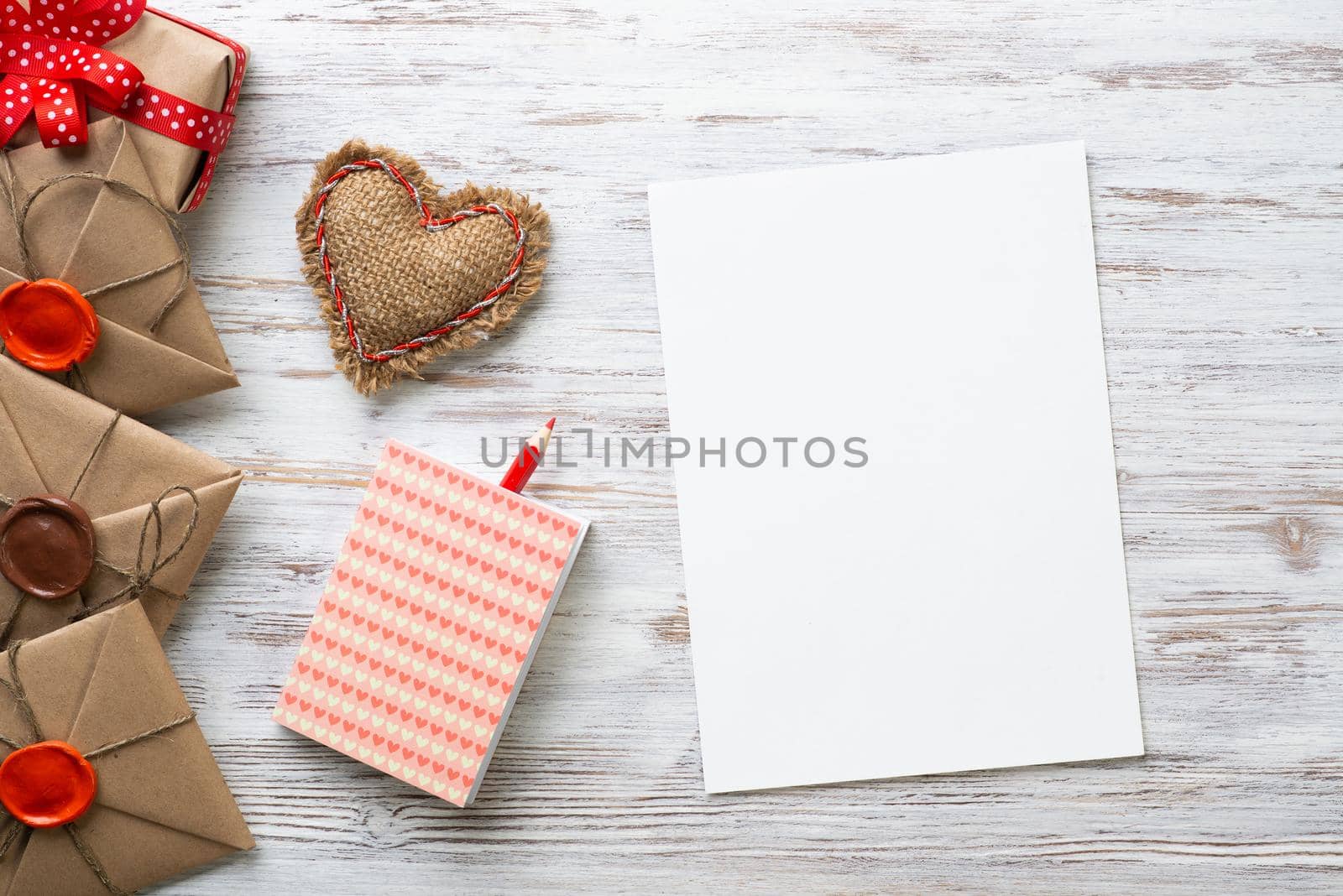 Flat lay cute composition with handmade fabric heart. White paper and retro mail envelopes on wooden table. Happy birthday or anniversary congratulation. Romantic message template with copy space