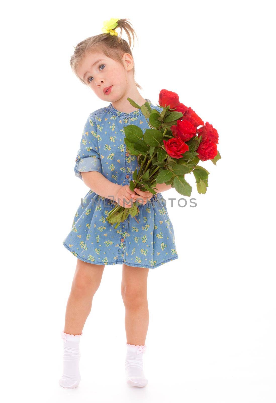 Charming girl in blue dress with a bouquet of red roses