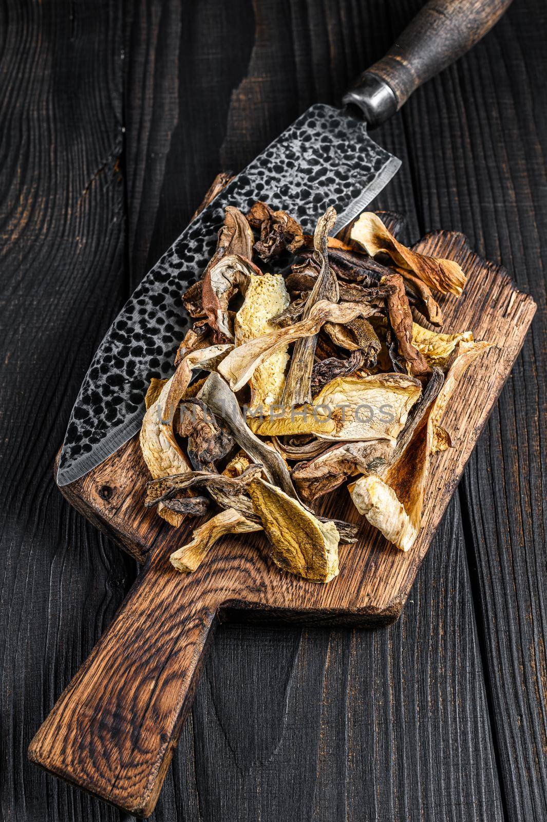 Sliced Porcini wild dried mushrooms on a wooden cutting board. Black wooden background. Top view by Composter