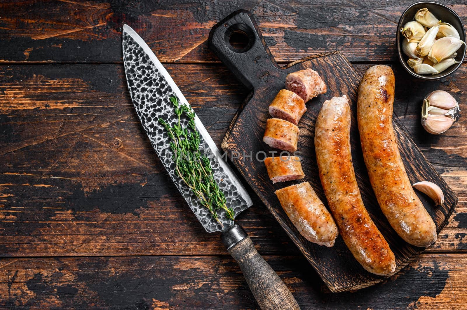 Fried and sliced pork Sausage with herbs. Top view. Dark wooden background. Copy space.