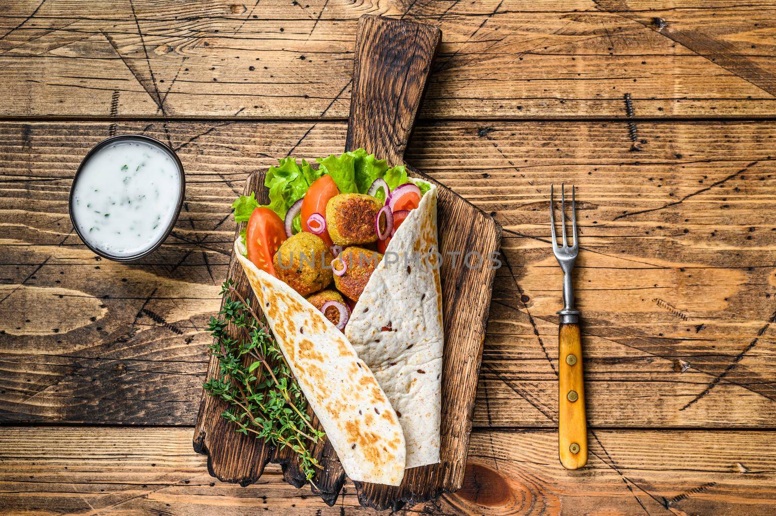 Vegetarian Tortilla wrap with falafel and fresh salad, vegan tacos. wooden background. Top view by Composter