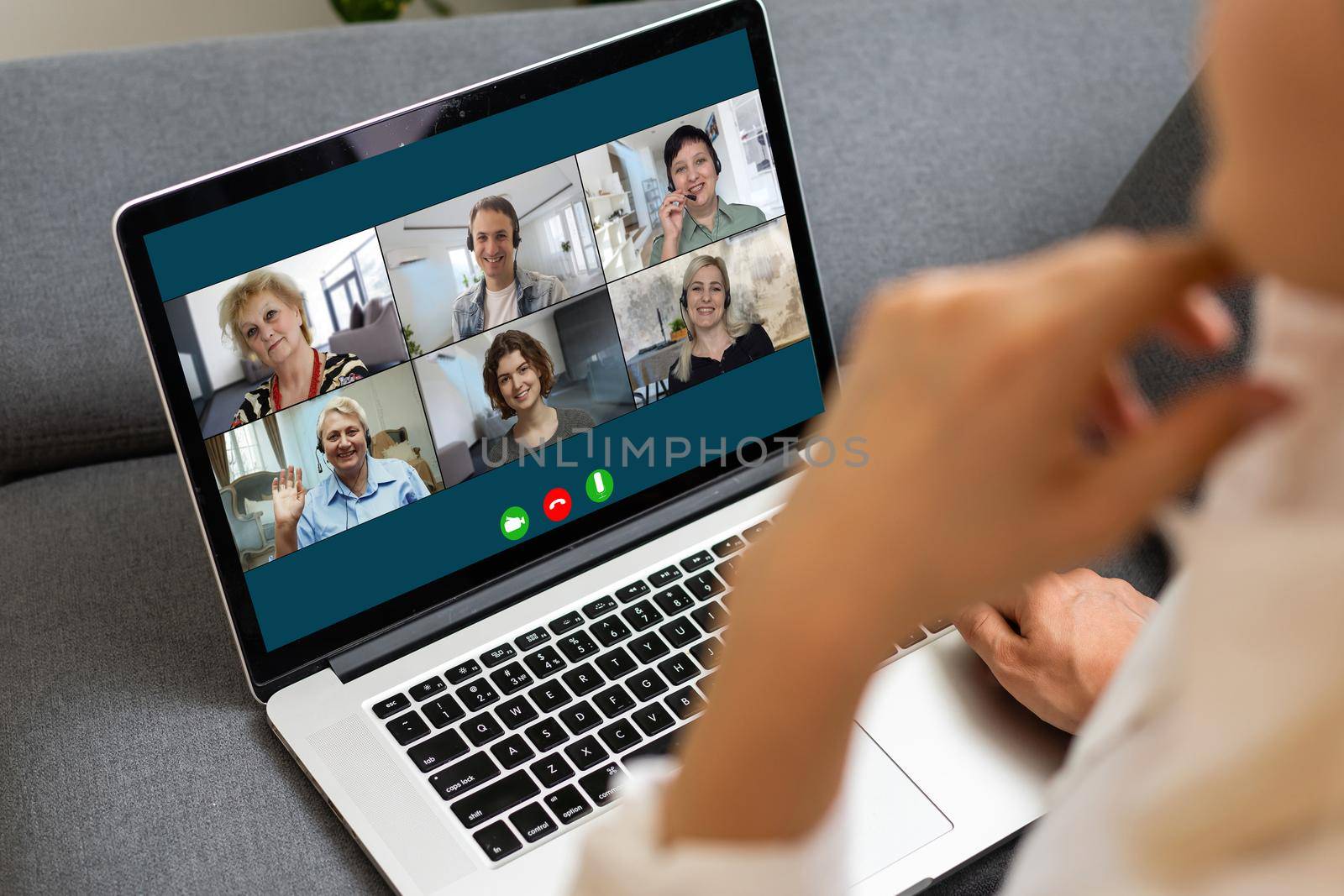 View over businesslady shoulder seated at workplace desk look at computer screen where collage of many diverse people involved at video conference negotiations activity, modern app tech usage concept by Andelov13