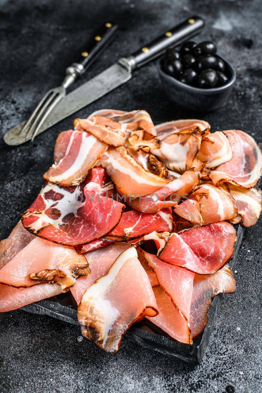 Set of cold cured italian meat Ham, prosciutto, pancetta, bacon. Black background. Top view by Composter
