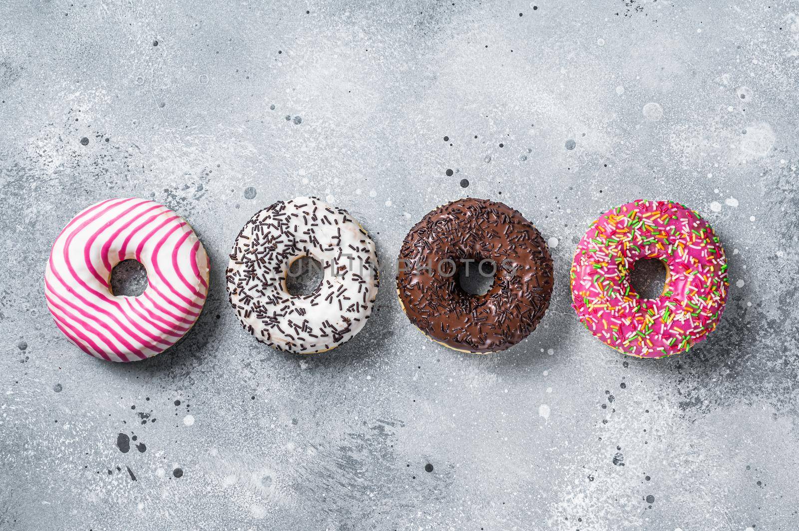 Assorted glazed donuts on a kitchen table. Gray background. Top view by Composter