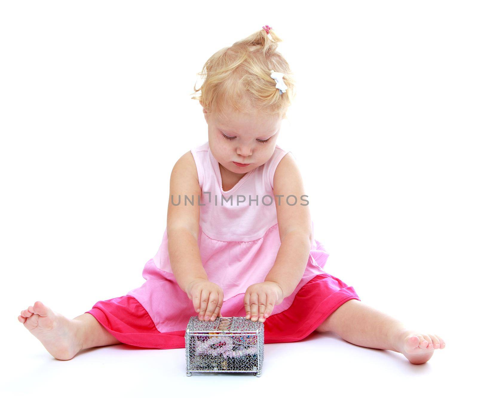 Little girl looks at what is in the box. Isolated on white background .