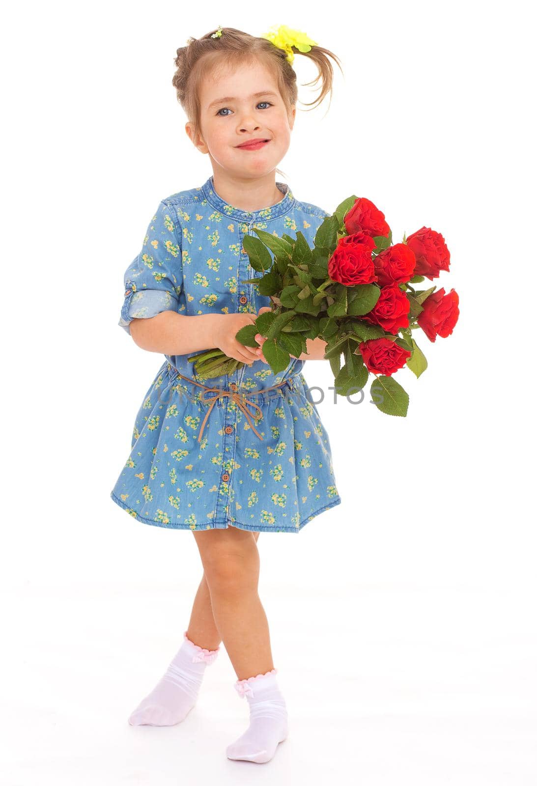 Little girl in a blue dress buttoned holding a bouquet of roses