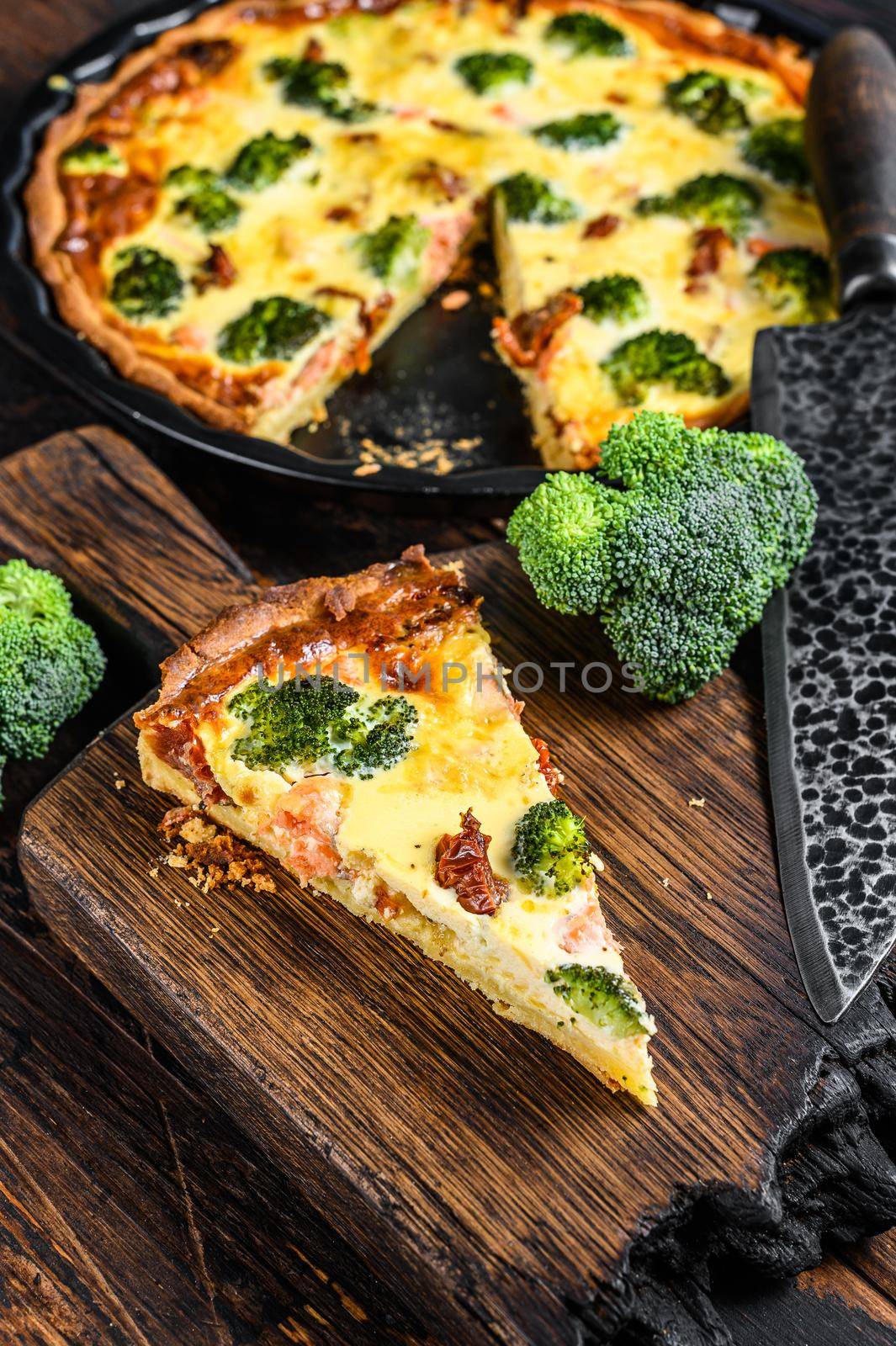 Quiche tart with smoked salmon, broccoli and spinach. Dark wooden background. Top view by Composter