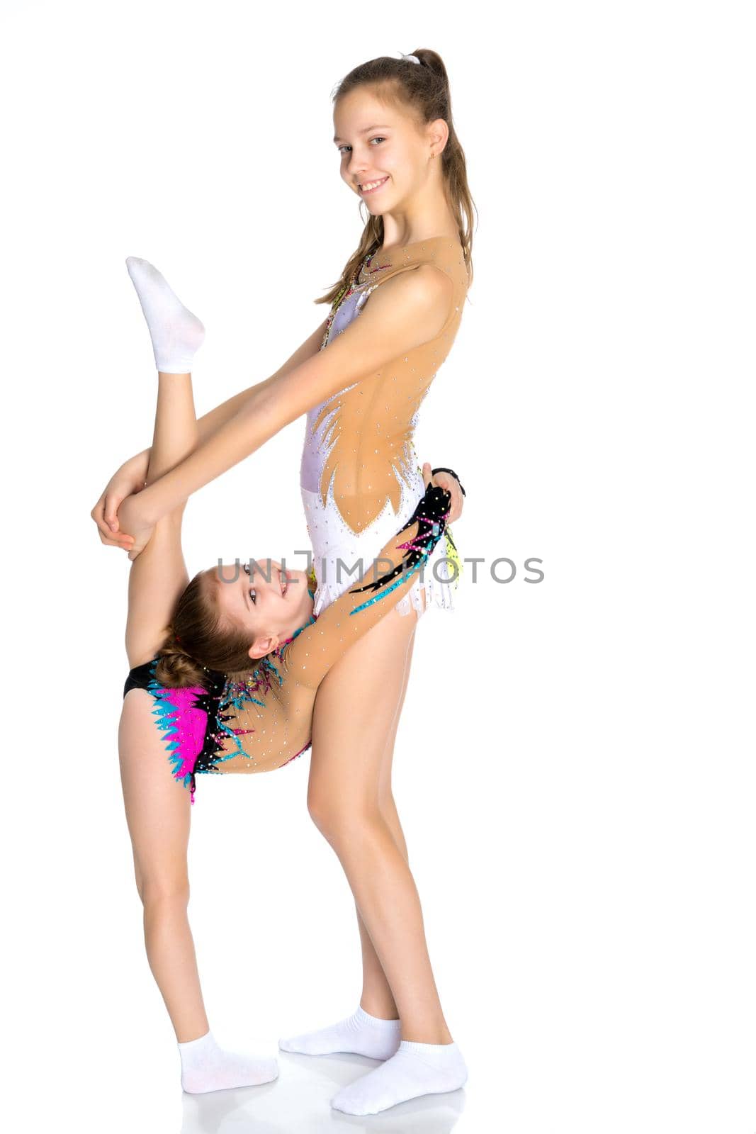 Lovely little girls gymnasts warm up before the competition. The concept of a happy childhood, sports and fitness. Isolated on white background.