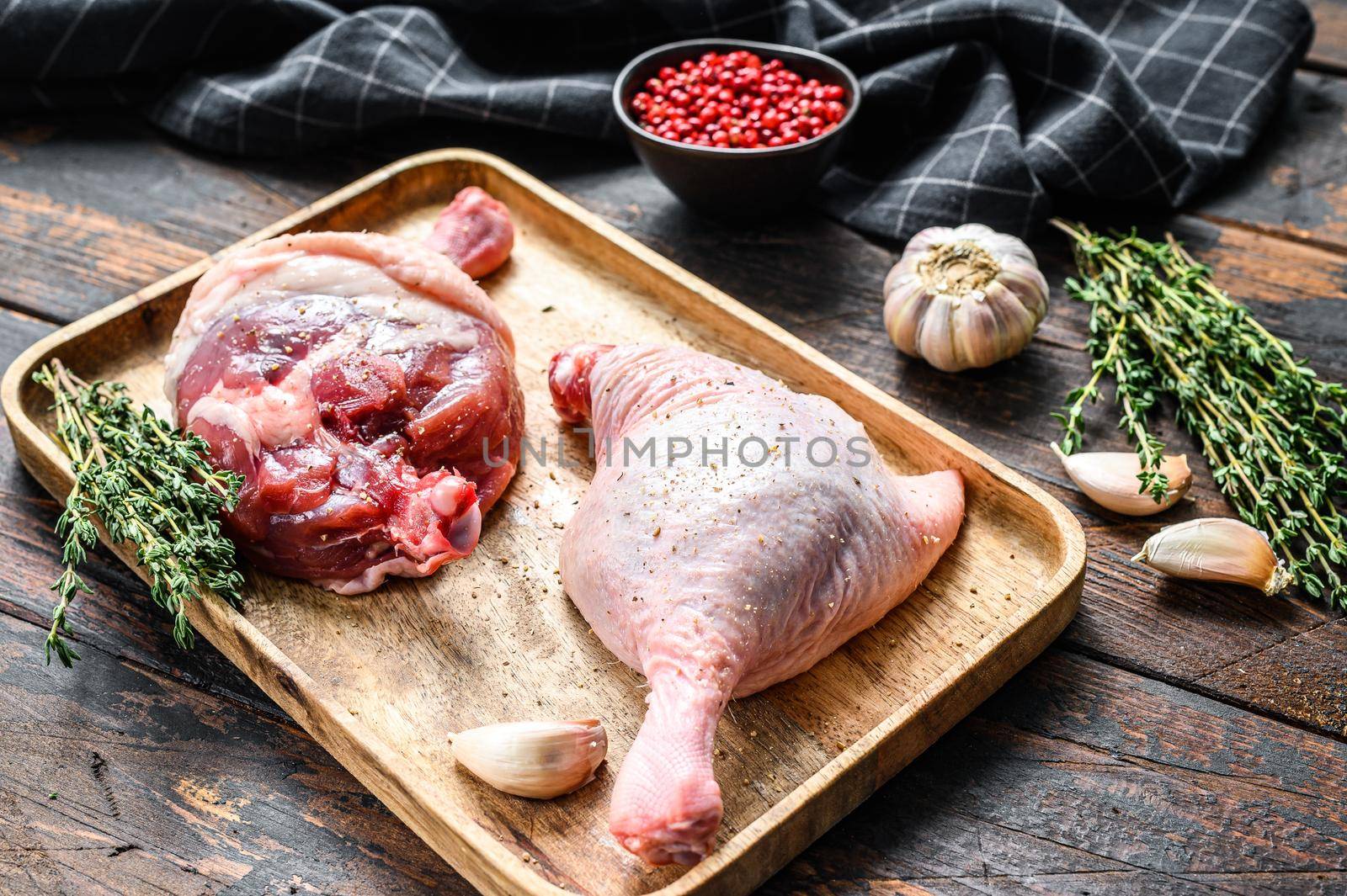 Duck legs on cutting board, Raw meat. Dark background. Top view.