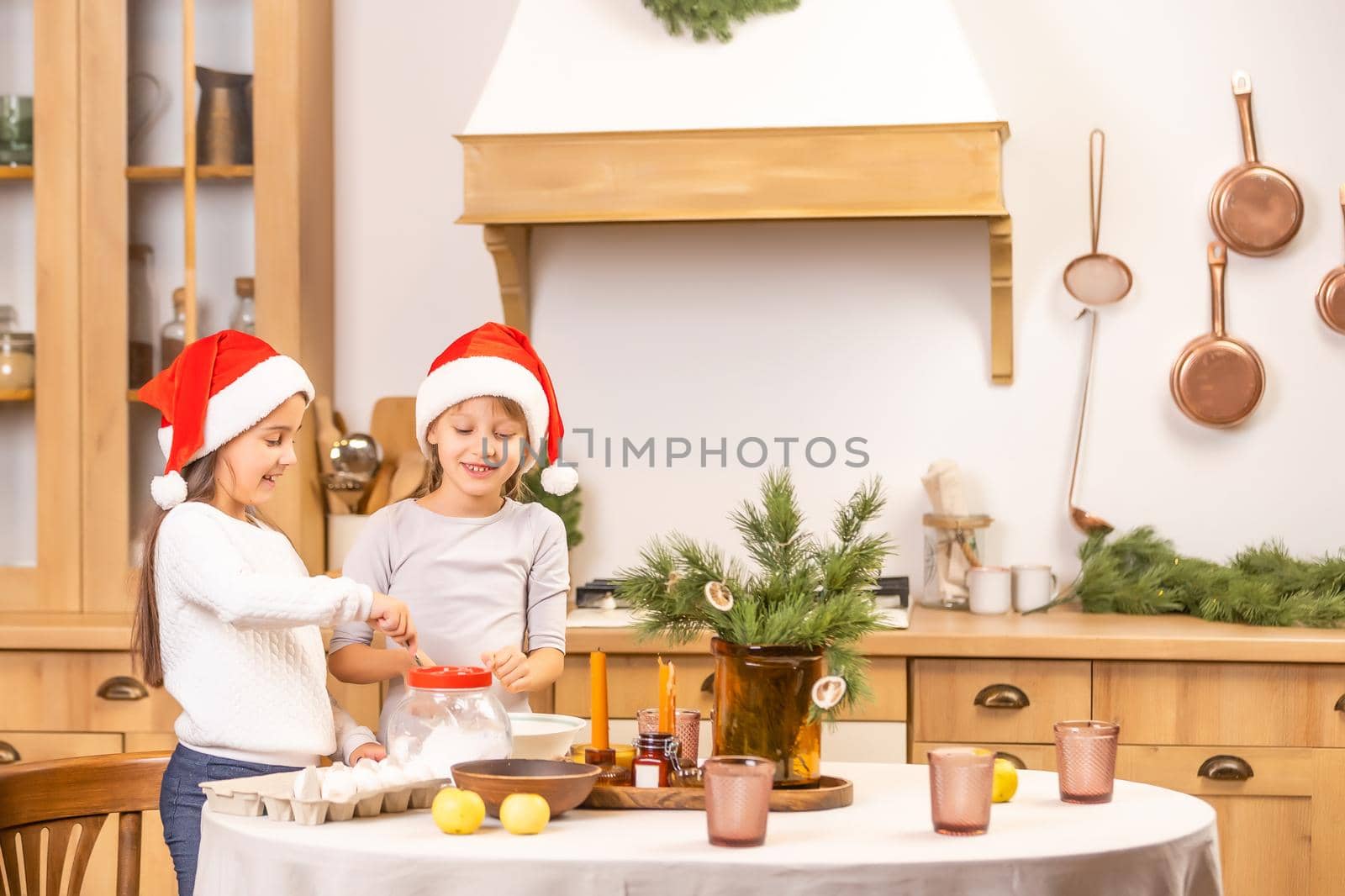 happy sisters children girls bake cookies, knead dough, play with flour and laugh in the kitchen