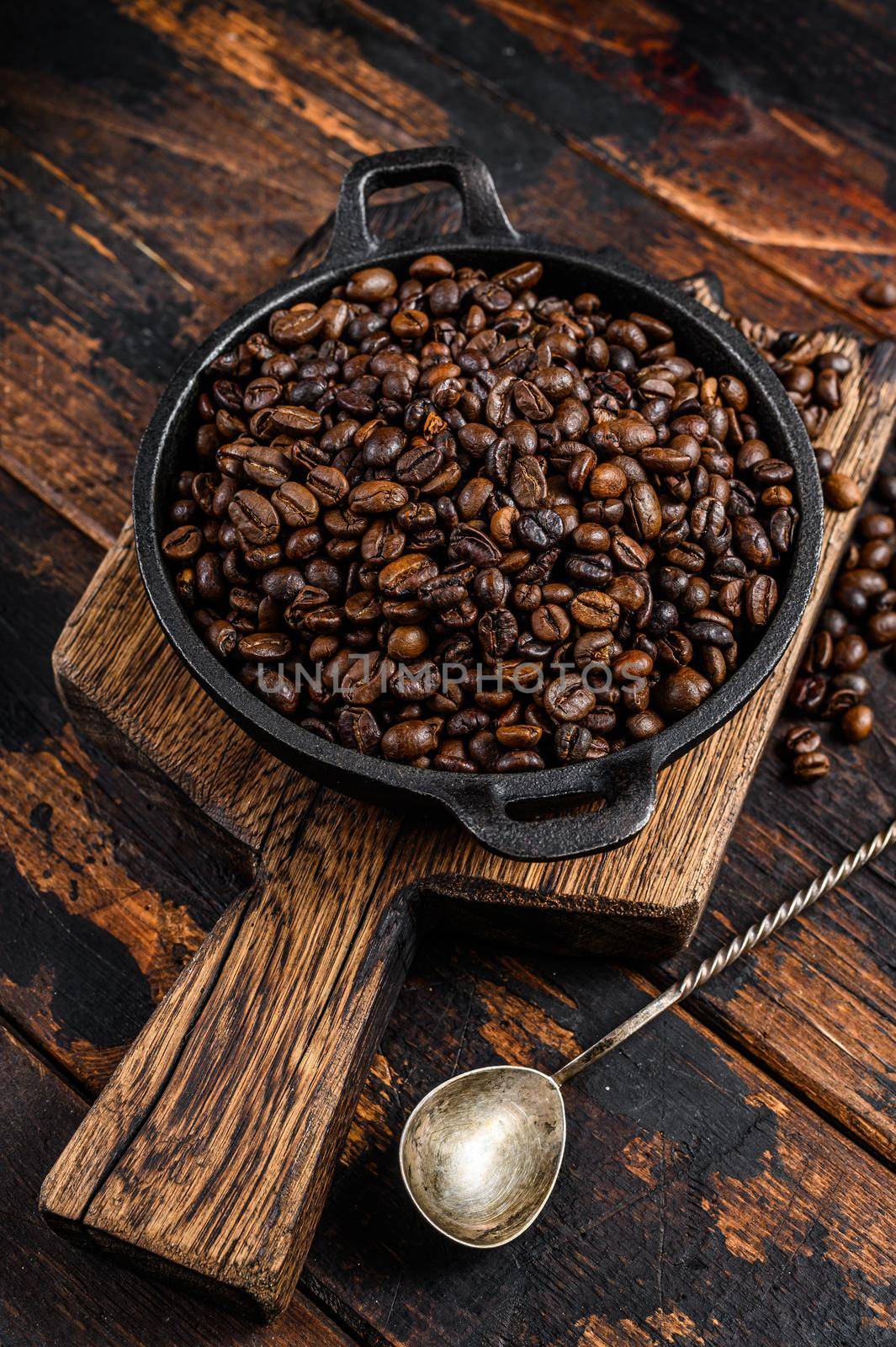 Dark roasted Coffee beans in a pan. Dark wooden background. Top view.