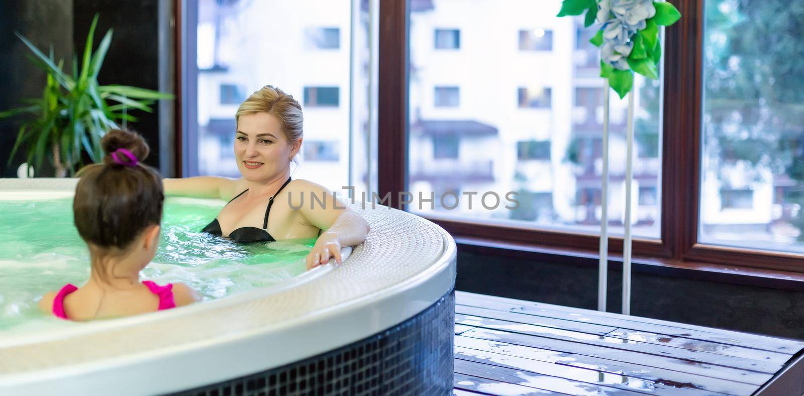 Mother and daughter relaxing in private jacuzzi. People smiling. Travel, summer and family concept.
