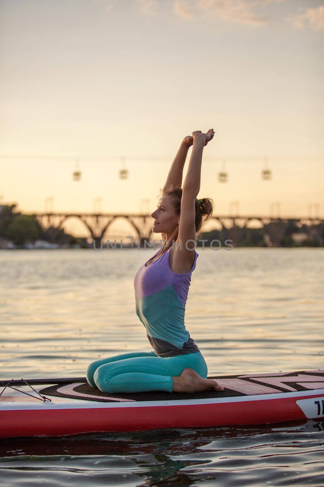 Young beautiful woman meditating in a sea at SUP paddleboarding. Healthy lifestyle. by nazarovsergey