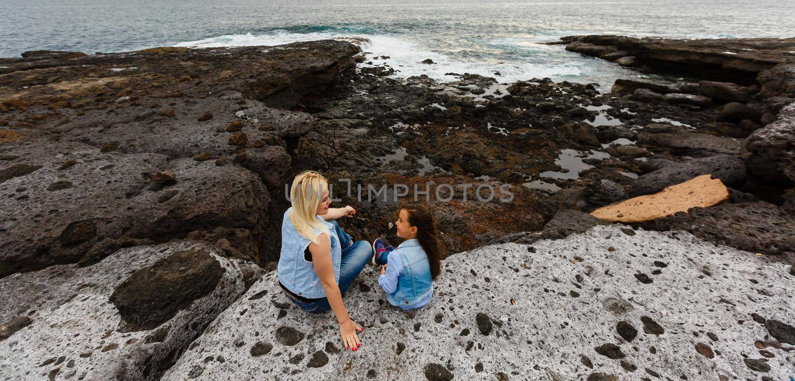 mother and daughter are walking near the ocean on the island of tenerife by Andelov13
