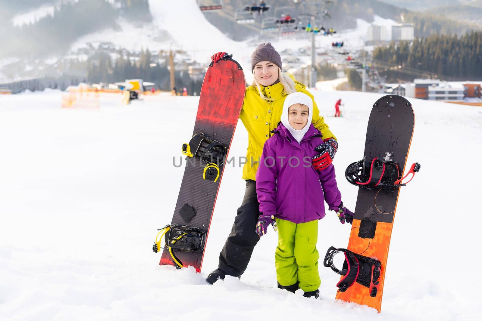 Mother and daughter with snowboards are playing in the snow