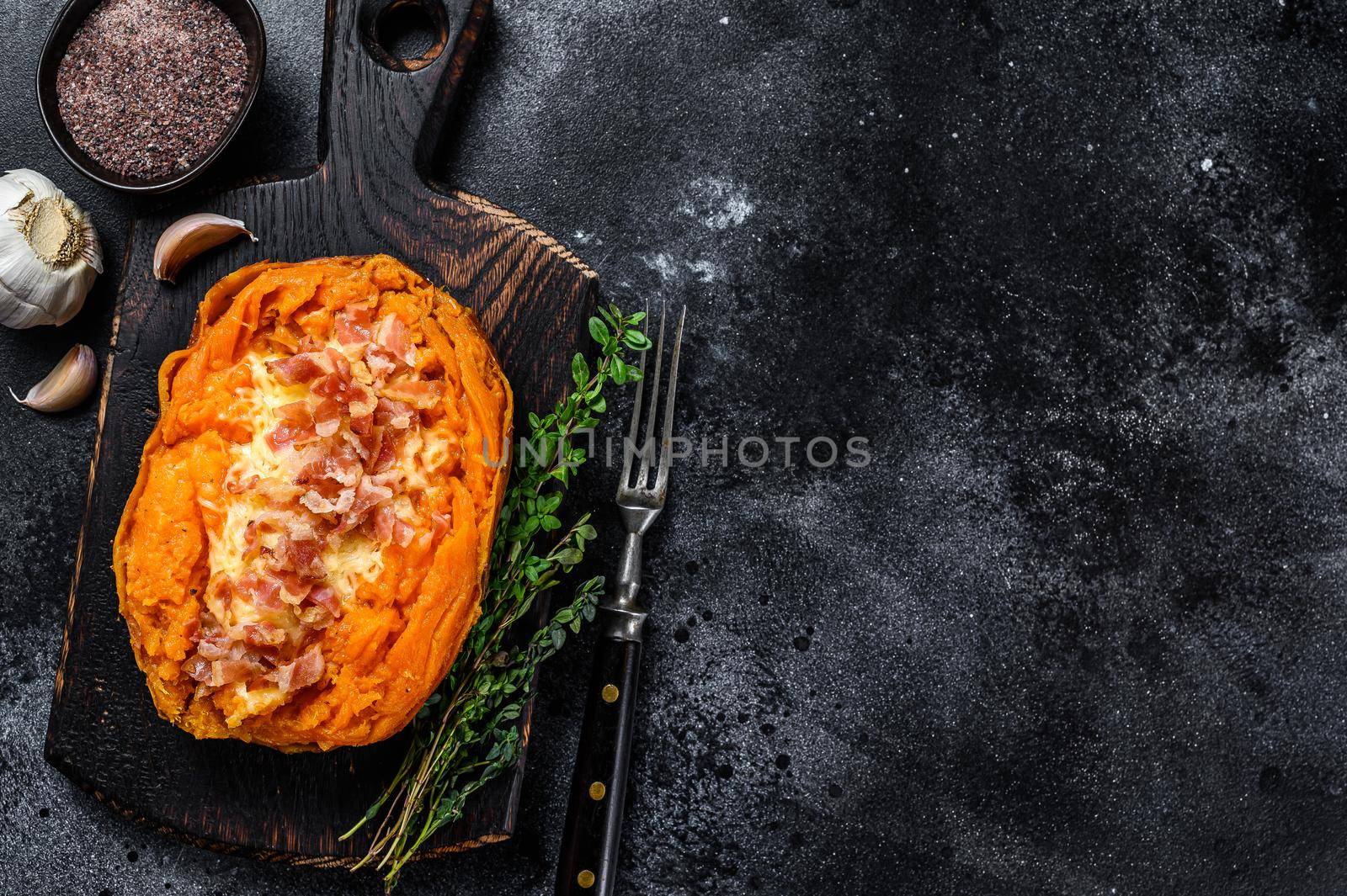 Baked sweet potato yam stuffed with ground beef and cheese. Black background. Top view. Copy space.