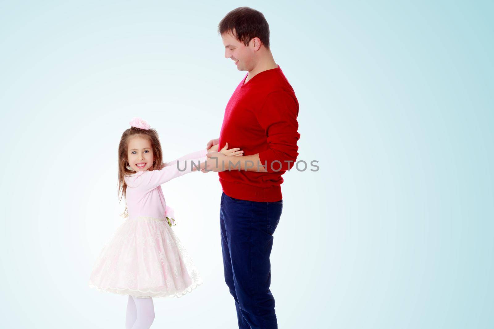 Cute little long-haired girl in a smart pink dress , reaches out to his dad.