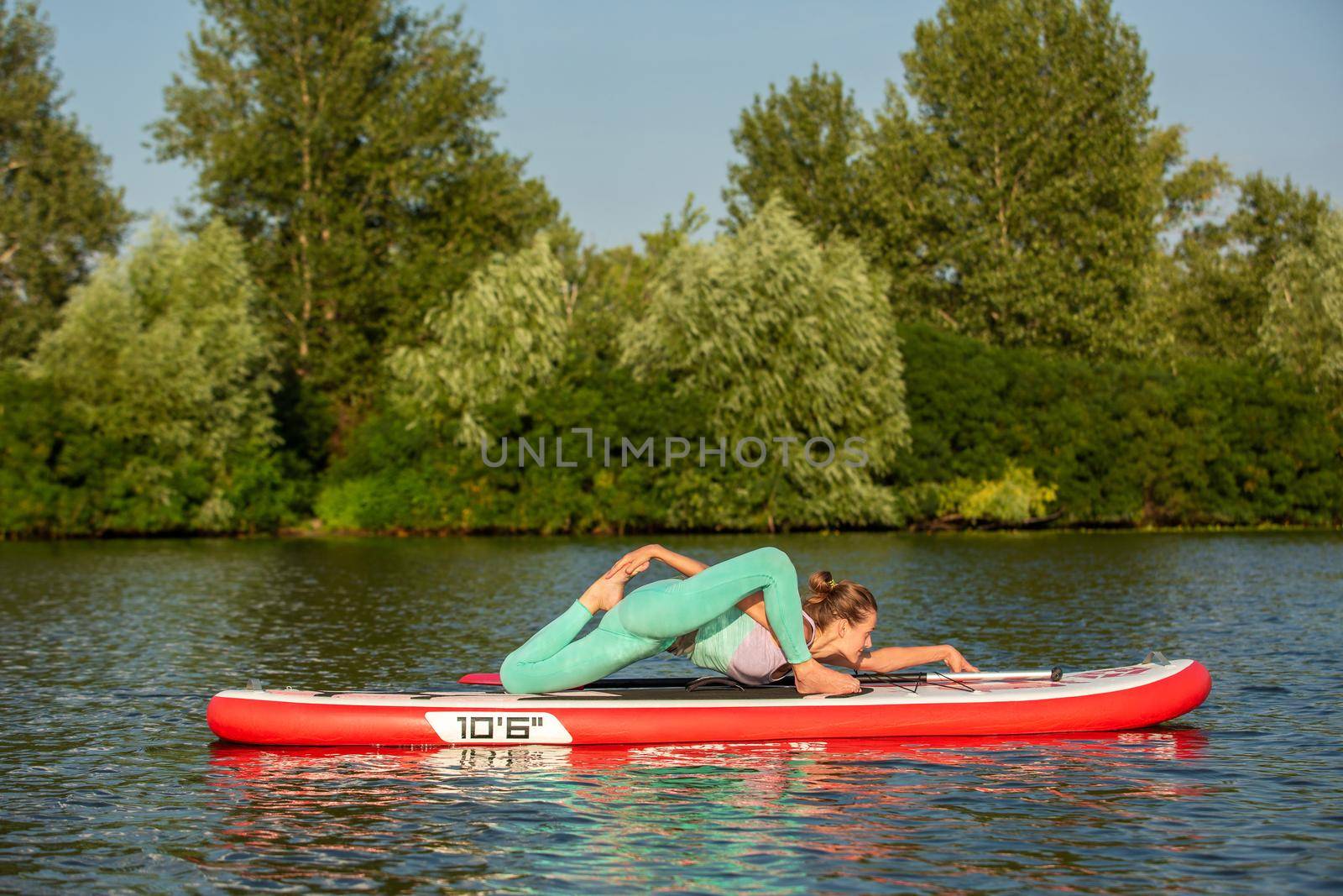 Woman practicing yoga on the paddle board in the morning. Sport. Hobby. Yoga.