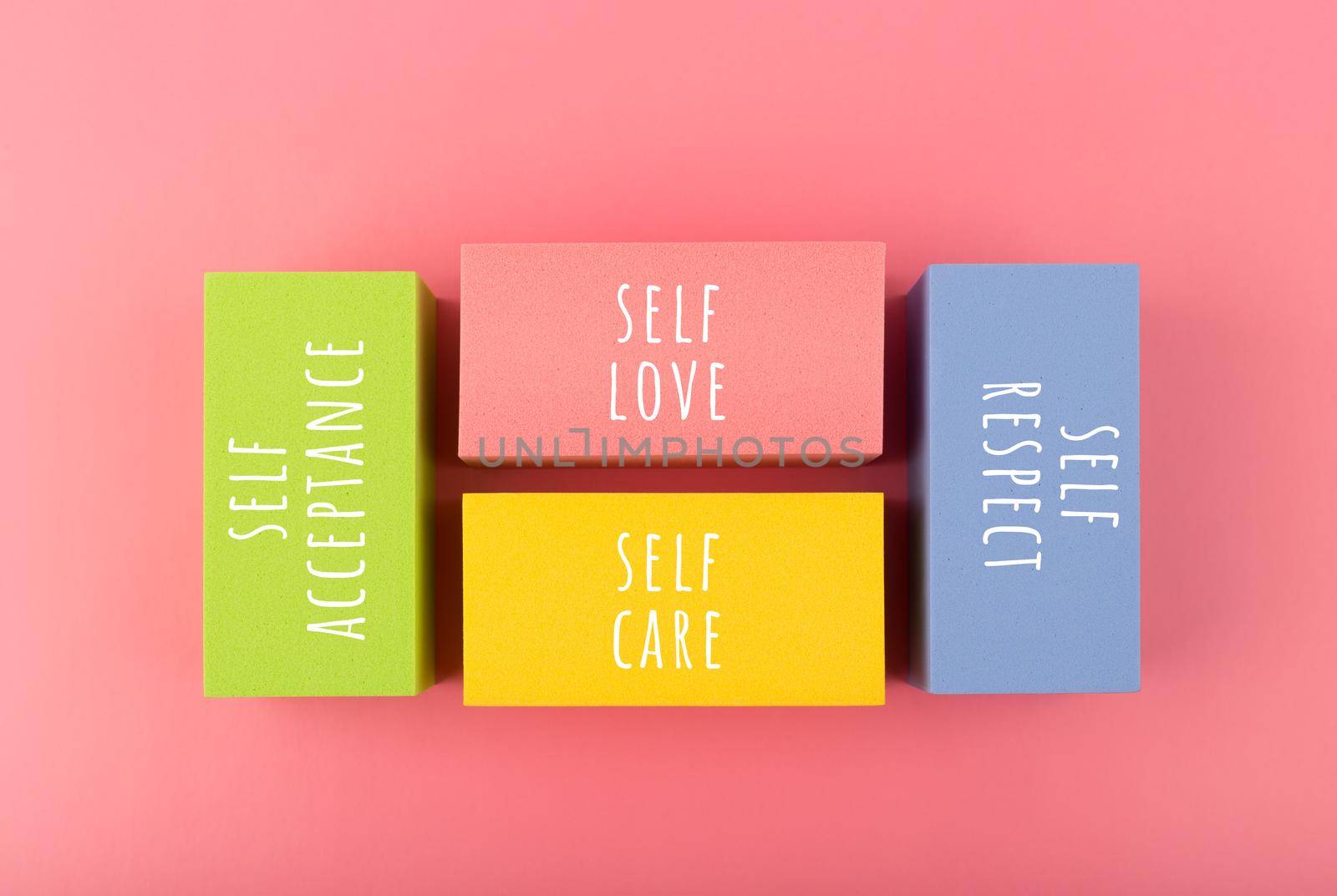 Self respect, acceptance, care and love written on multicolored rectangles on pink background. Mental and psychological health self love and wellness concept.
